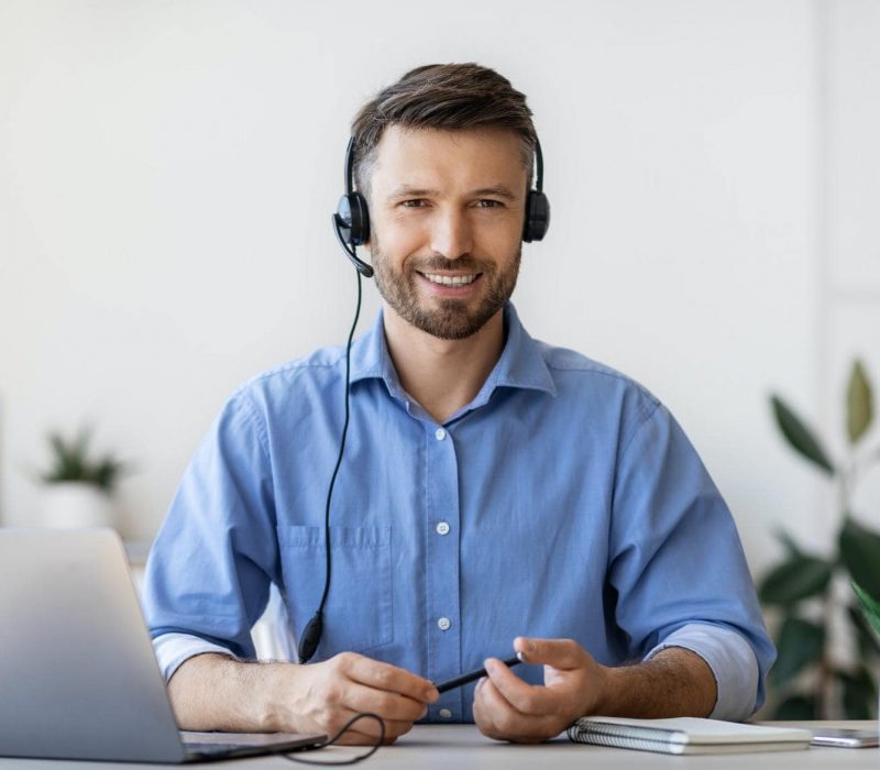 Portrait of smiling male customer service operator in headset at workplace